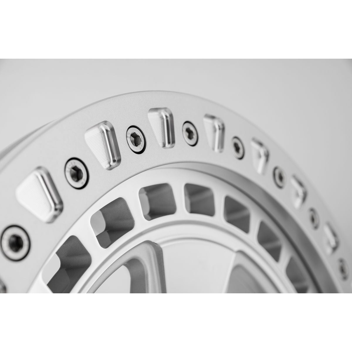 Close up of beadlock on silver forged alloy off-road wheel for Porsche Cayenne on a white background.