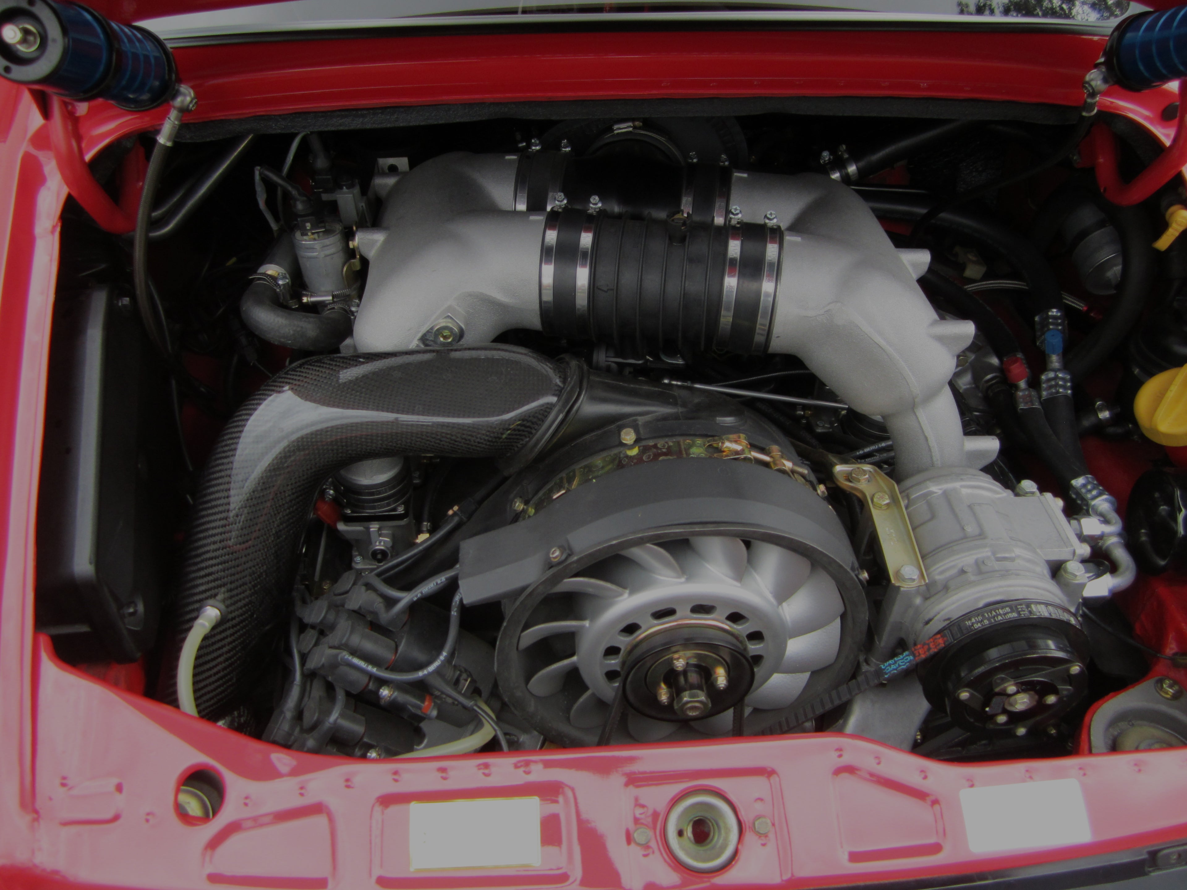 Porsche 911 air-cooled engine with visible components in a red engine bay.