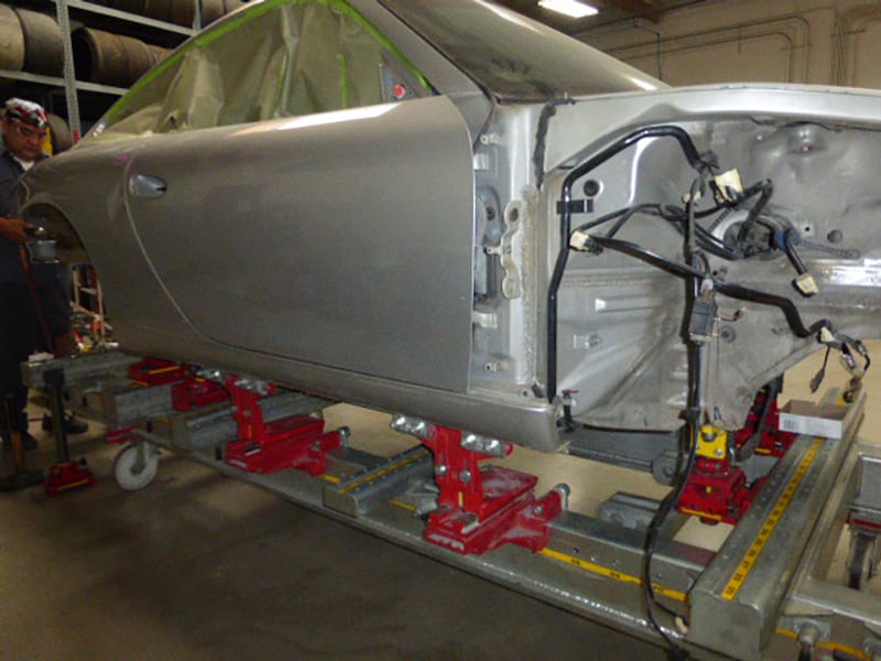 Close-up of a Porsche 996 911 door with door handle removed and windows masked off for paint prep.