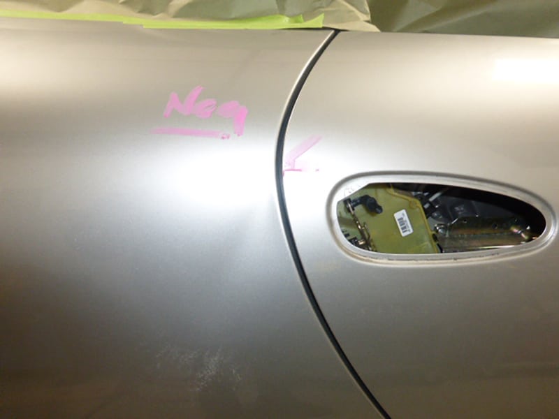Close-up of a Porsche 996 911 door with door handle removed and windows masked off for paint prep.