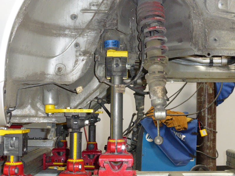 Porsche suspension system being worked on with tools and equipment.