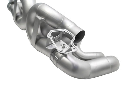 Close up of Soul Performance center muffler bypass X-pipe valved exhaust system in silver for Porsche 911 on a white background.
