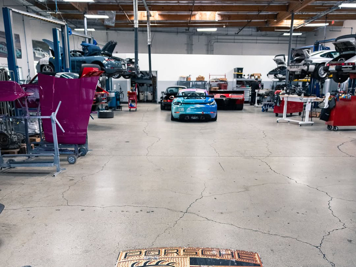 911 Design automotive repair shop with cars and equipment inside a large open garage shop.