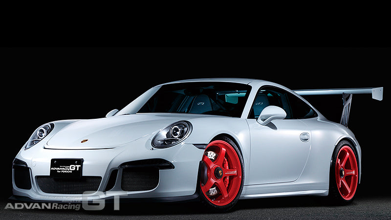 White Porsche 991 GT3 with red Advan GT for Porsche wheels in black background.