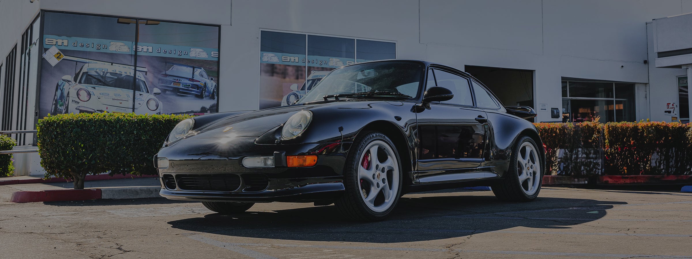 Black Porsche 911 parked in front of 911 Design building.