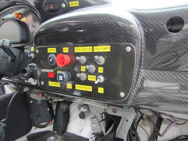 Close-up of 911 Design race car interior carbon fiber dash with control switches and labels.