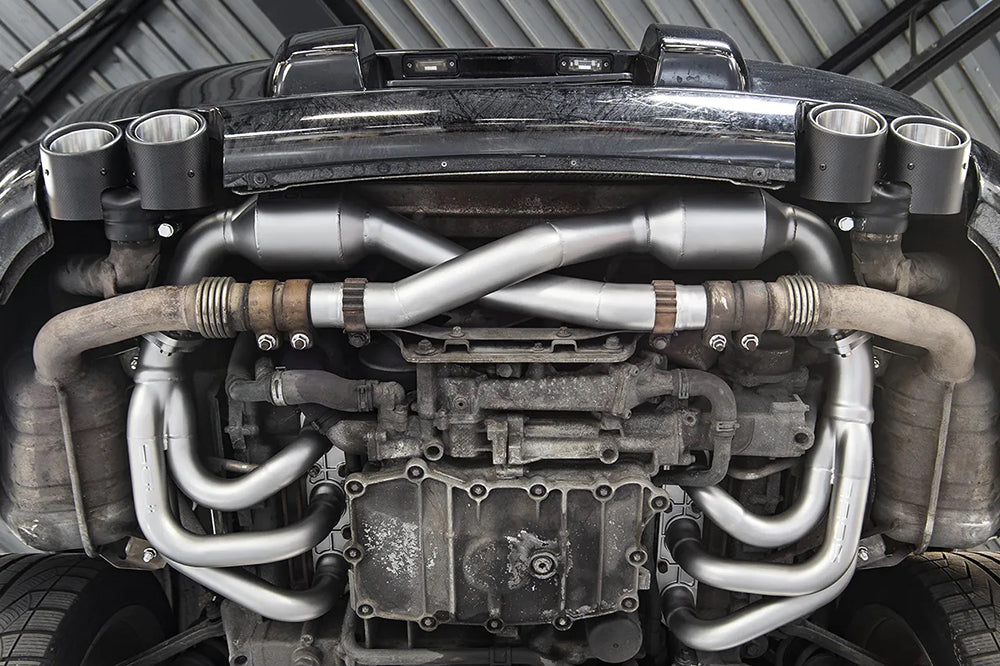 Close-up of a Soul performance competition headers installed on a Porsche on a garage lift.