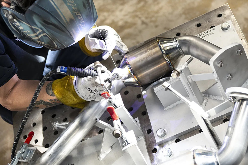 Person welding Soul performance sport catalytic converter for Porsche.