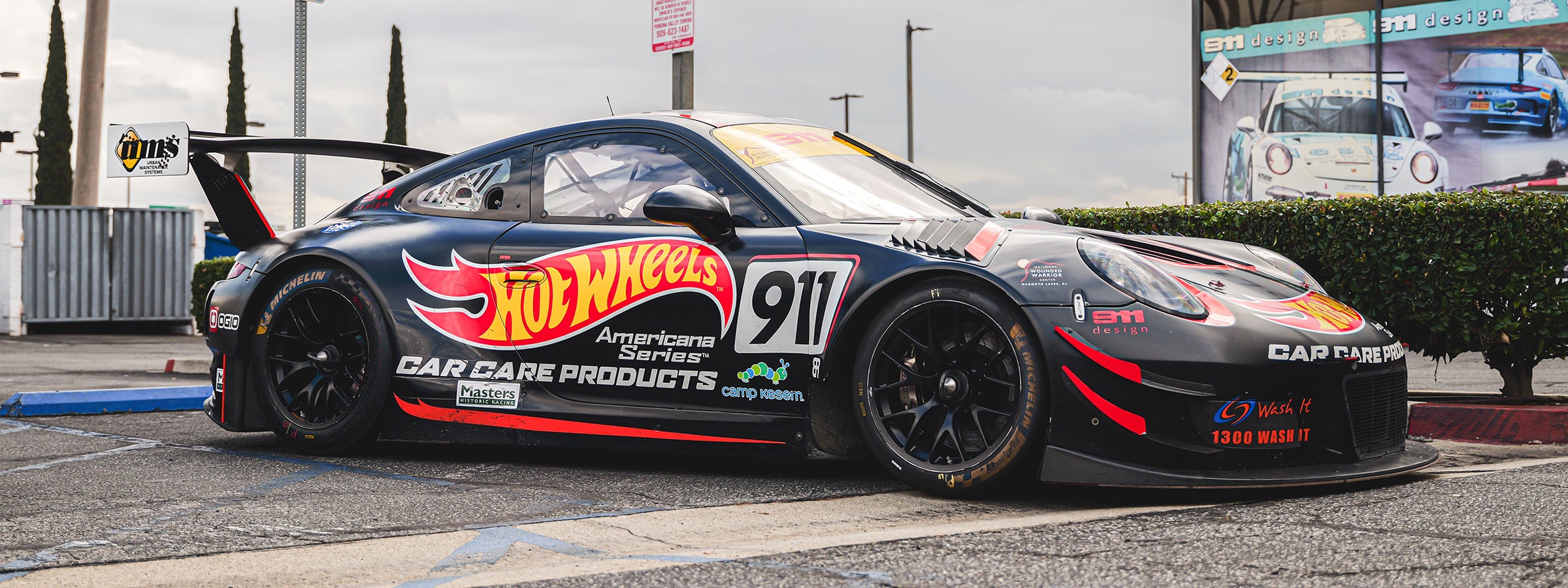 Hot Wheels branded 911 race car parked outside 911 design building.