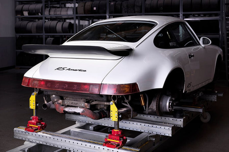White Porsche 911 RS America on a chassis roller for body shop.