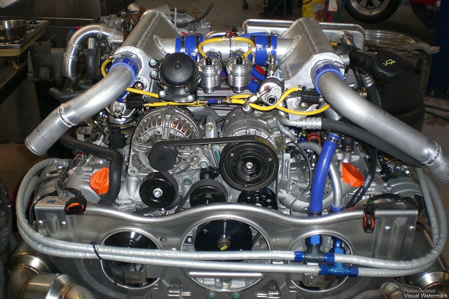 Close-up of a high-performance Porsche 911 race car engine with various components and piping.