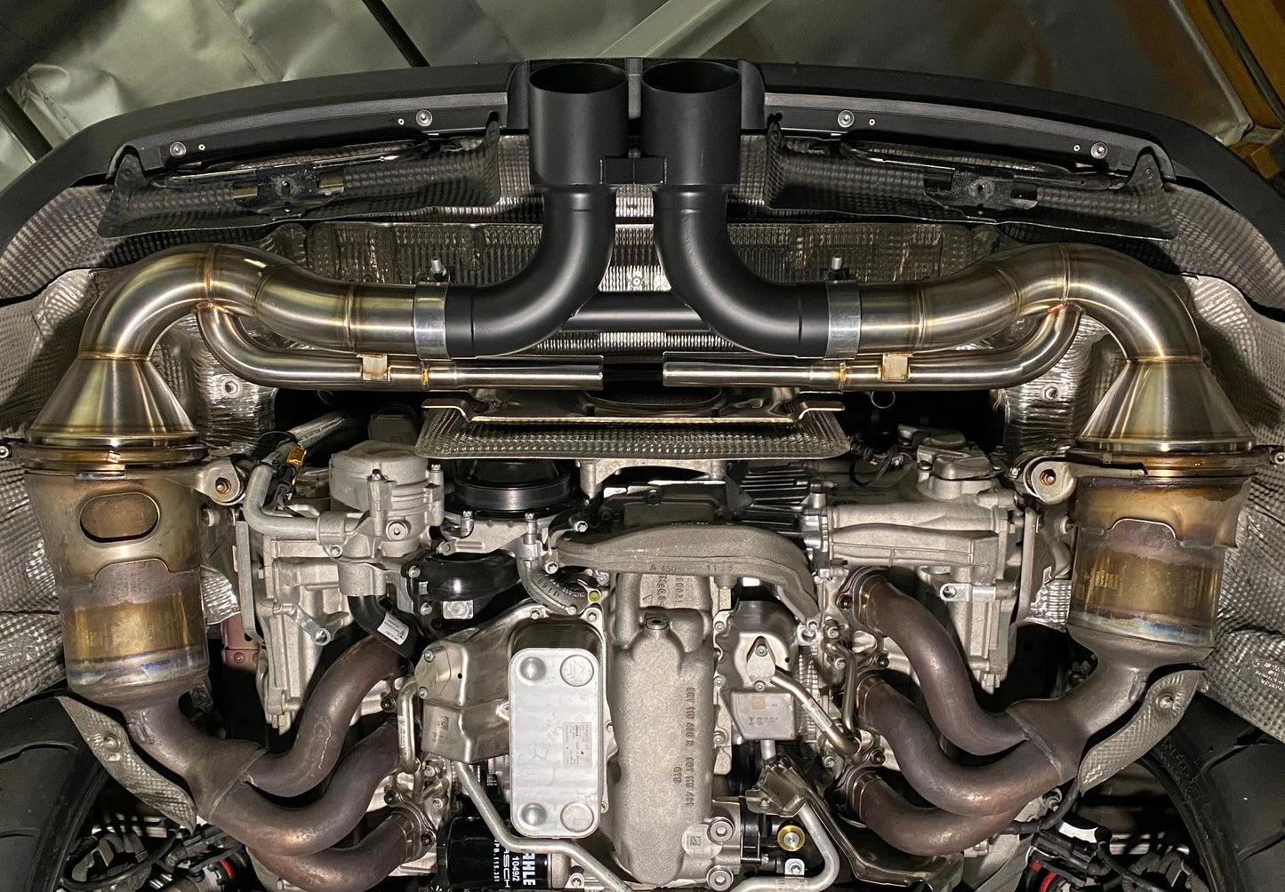 Shark Werks titanium center muffler bypass exhaust with black exhaust tips installed on Porsche 911 GT3 engine.