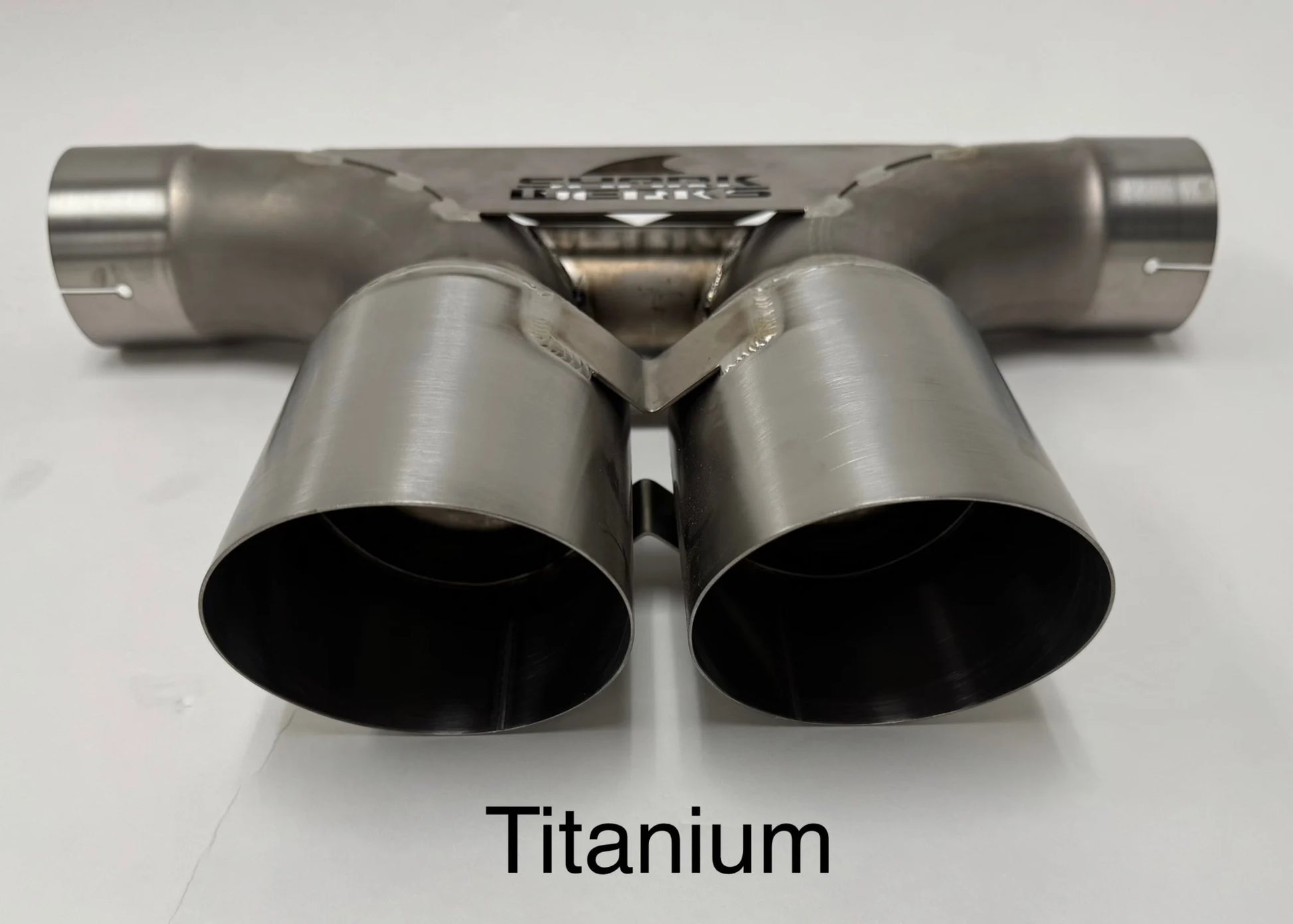 Close up of Shark Werks titanium center muffler bypass exhaust with exhaust tips on white background.